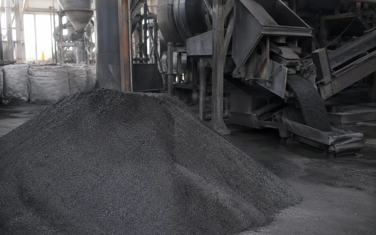 Pile of fine dark graphite powder discharged inside a grinding plant