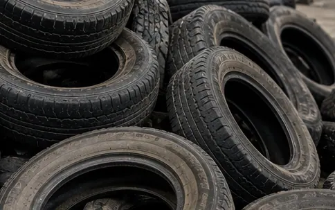 Stack of end-of-life tyres at the feed end of a rubber recycling line
