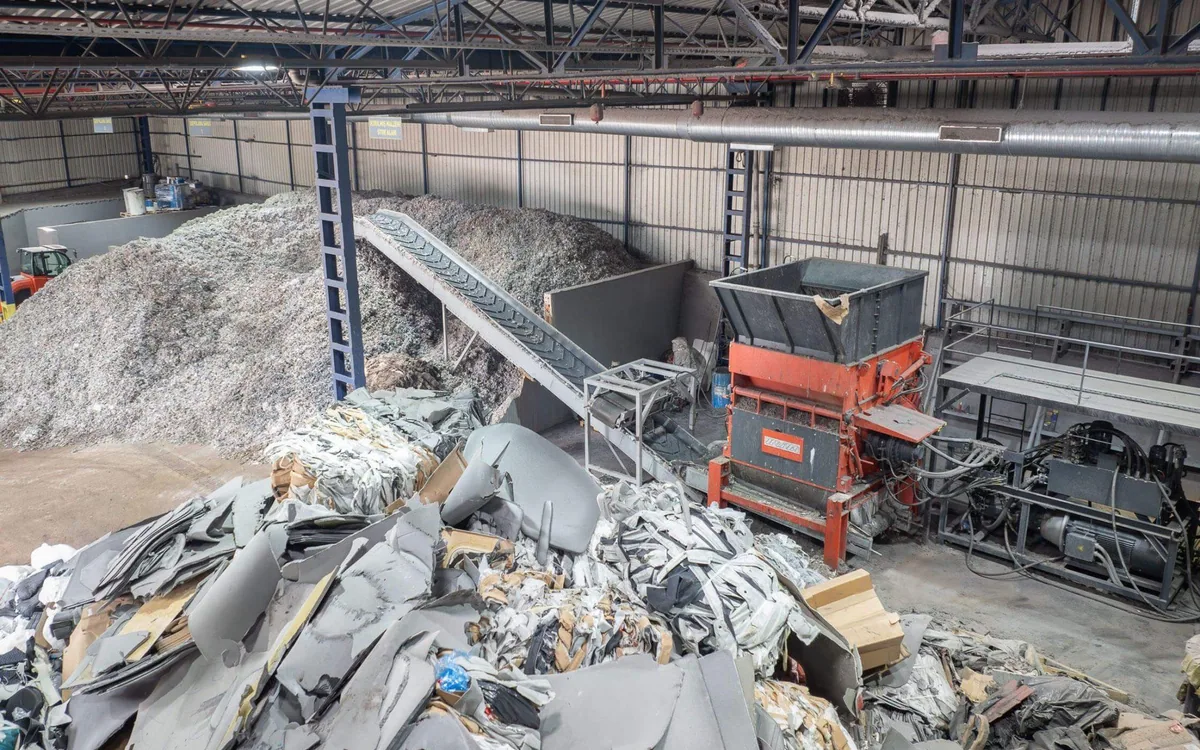 Mixed industrial waste fed to a shredder inside a recovery plant