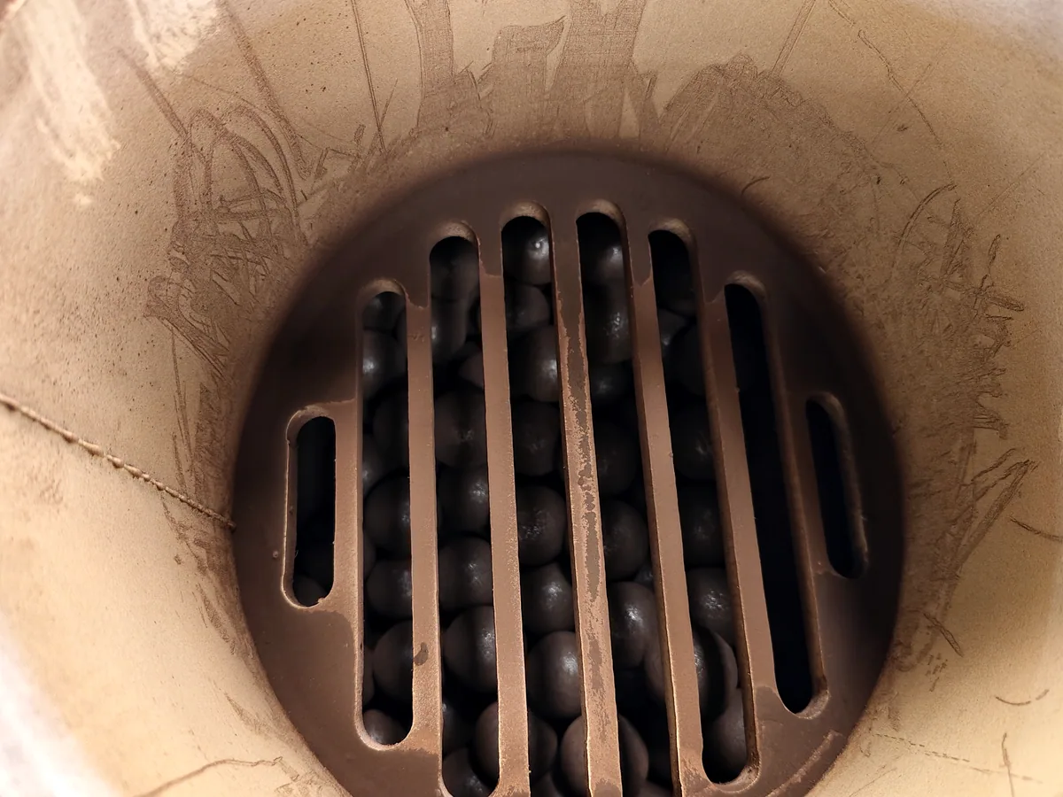 Ball mill discharge grate seen from inside the shell, with the steel grinding media charge behind the slots
