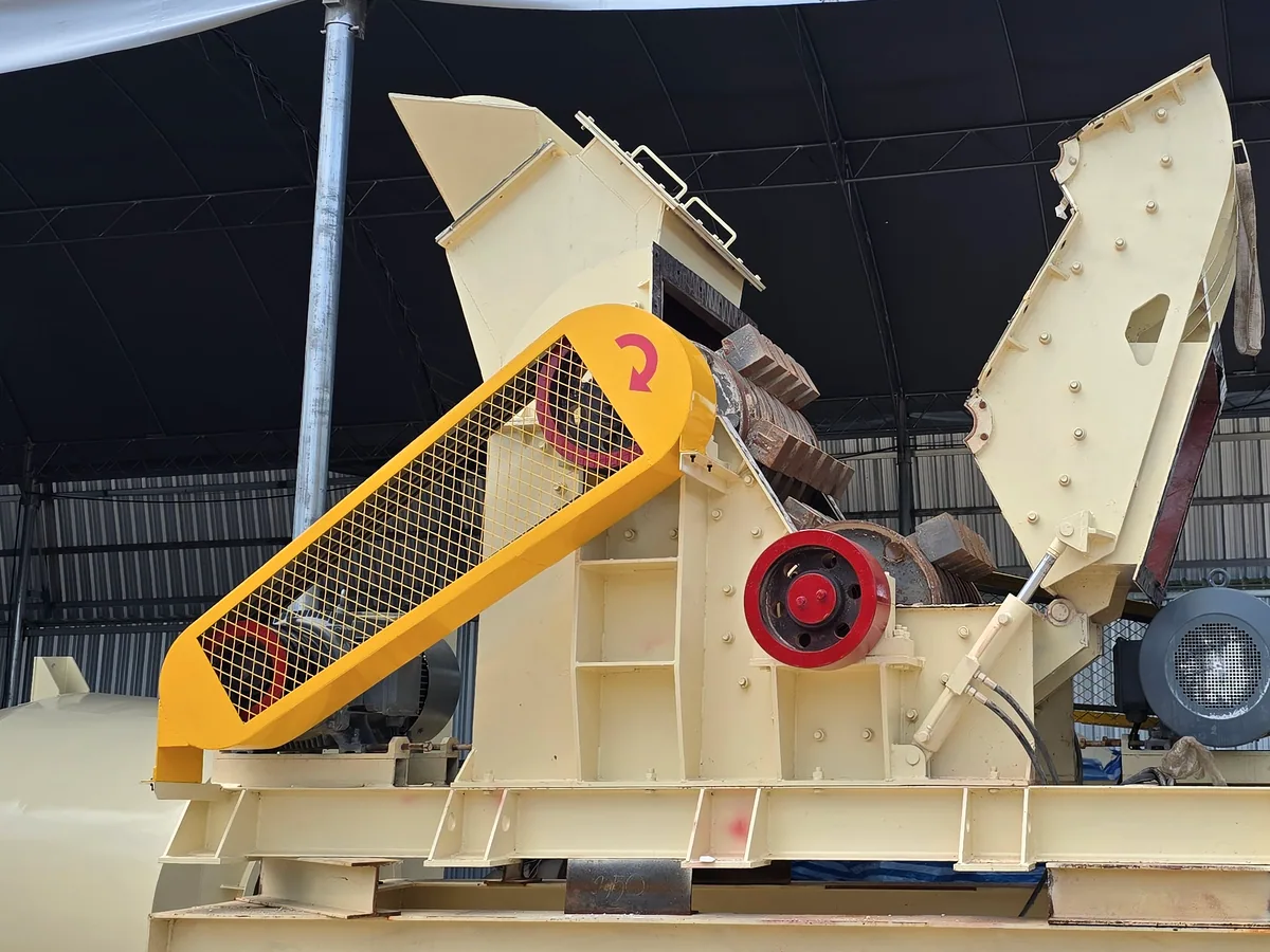 Hammer mill with the inspection door swung open, exposing the swing-hammer rotor and yellow belt guard