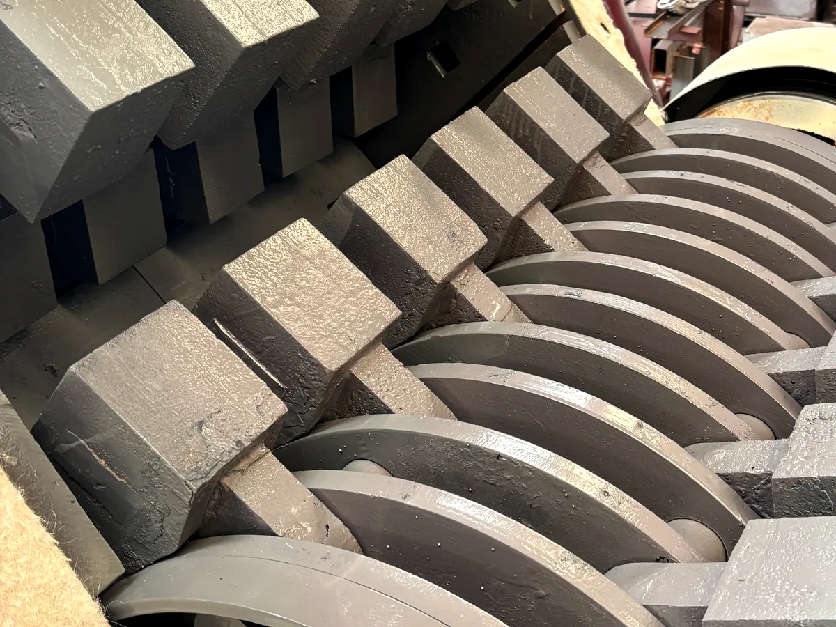 Hardened swing hammers and spacer discs on a THOR hammer mill rotor, seen through the open housing