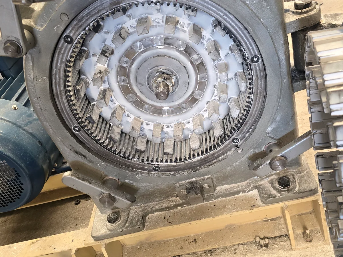 Pin mill opened for inspection, showing the intermeshing rotor and stator pin rings and the drive motor